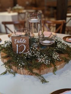 the table is decorated with greenery, candles and place cards for guests to sit on