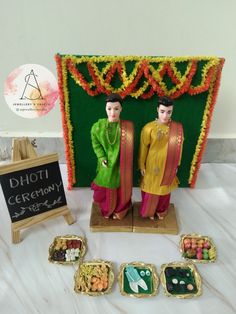 two figurines are standing next to each other in front of a display of food