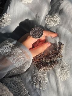 a woman's hand holding something in her left hand on a lace covered surface