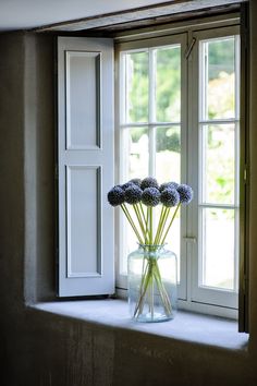 a vase filled with purple flowers sitting on top of a window sill