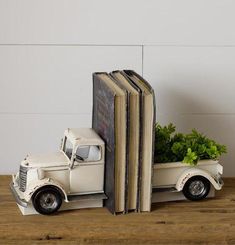 an old truck with a planter in the bed is sitting on a wooden table