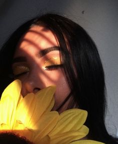 a woman with long black hair holding a yellow flower