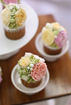 three cupcakes with flowers on them sitting on a table