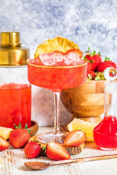 a drink in a glass with fruit on the side and other ingredients around it, including strawberries