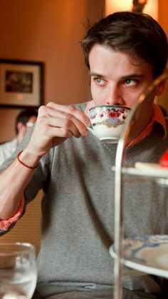 a man sitting at a table drinking from a cup