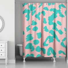 a bathroom with a pink and green shower curtain next to a white dresser in front of a mirror