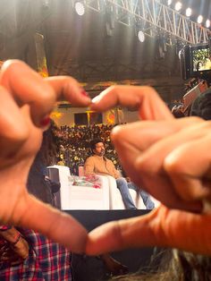 two hands making the shape of a heart in front of an audience at a convention