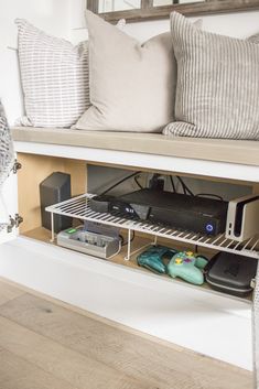 an entertainment center under a bed with pillows and other items on the shelf next to it