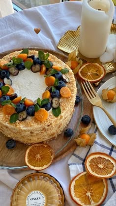 a cake with fruit on it sitting on top of a wooden table next to plates and utensils