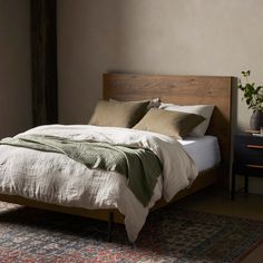 a bed with two pillows on top of it next to a night stand and table