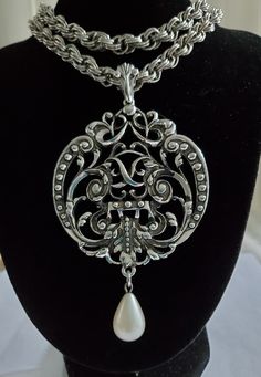 Vintage Avon Filigree Design Statement Pendant Necklace with a Modern Twist. This substantial chunky rolo chain suspends a cut out design with faux pearl tear drop adding a classic touch. The pendant is signed and is 4 inches in length and 2 3/8 inches in width and offers a ornate bail. The chain drapes at 18.5 inches around the neck. Previously owned and in great condition and  from  a 1980's collection.   Combine with another item and get free shipping!! Avon Vintage, Design Statement, Filigree Design, Statement Pendant, Vintage Avon, Cut Out Design, Rolo Chain, Free Gift Wrapping, Tear Drop