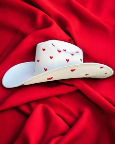 Darling features the most precious little red hearts adorning the crown and under the brim of a hard white canvas cowboy hat Proudly American Made. Our hats are manufactured in Mexico and details added by hand in Los Angeles, CA using the highest quality materials. SIZING S/M 19in-22.75in | 48cm-57.5cm L/XL 19.5in-23.25in | 49.5cm-59cm **Please allow up to 2 weeks for production and shipping.* If you need your order rushed, please send us an email. We can almost always accommodate rushed orders White Country Top Hat With Curved Brim, White Brimmed Country Top Hat, White Brimmed Country Style Top Hat, White Country Style Top Hat With Curved Brim, Country Style White Brimmed Top Hat, White Flat Brim Top Hat For Rodeo, White Flat Brim Top Hat For Country Events, White Flat Brim Fedora For Western-themed Events, White Country Style Fedora For Rodeo