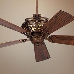 a ceiling fan with wooden blades and intricate designs