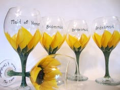 three wine glasses with sunflowers in them and the names of bridesmaids