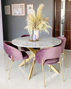 a dining room table with purple chairs and a white marble top in front of a gray wall