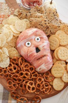 a plate with crackers, pretzels, bacon and cheese in the shape of a face