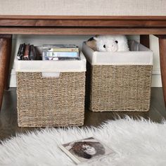 two wicker baskets under a table with a teddy bear in it and a magazine on the floor