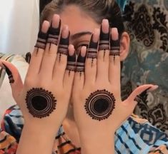 a woman with her hands covering her face and two rings on her fingers, while she is looking at the camera