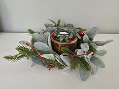 a candle is surrounded by greenery and red berries