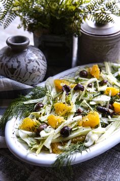 a salad with oranges and olives on a white plate