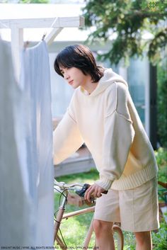 a woman is standing next to her bike and looking at something on the ground in front of her