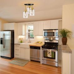 a modern kitchen with stainless steel appliances and wood flooring is pictured in this image