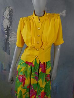 This 1980s yellow summer top has a band neckline and padded shoulders, and closes in the front with six yellow and gold buttons. Three buttons decorate each shoulder epaulet, and one button fastens the pleated yoke that falls from a gathered shoulder line to the waist. Bust = 38 inches (96cm) Shoulders = 16 inches (40.64cm) Waist = 32 inches (81.28cm) Sleeve Length = 11 inches (27.94cm) Top Length = 21 inches (53.34cm) Size label: 10 US, 14 UK Material label: 76% viscose, 24% polyester Sourced i Yellow Summer Top, Vintage Short, Yellow Top, European Vintage, Plaid Blazer, Size Label, Double Breasted Blazer, Vintage Shorts, Gold Buttons