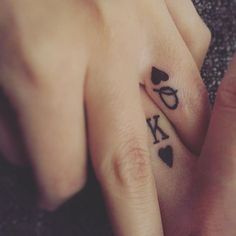 two people with tattoos on their fingers holding each other's hands and the word love written in cursive letters