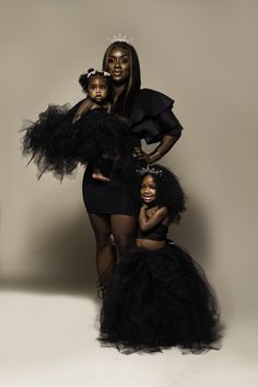 two women in black dresses and one is holding a small child with her arms around her