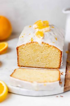 a loaf of lemon pound cake with icing and oranges around it