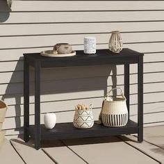 an outdoor table with vases and baskets on it next to a house siding wall