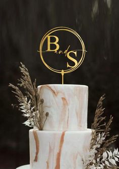 a three tiered white cake with gold lettering on top