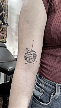 a woman's arm with a globe tattoo on the left side of her arm