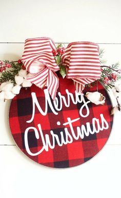 a red and black plaid christmas ornament hanging on a white wall with cotton flowers