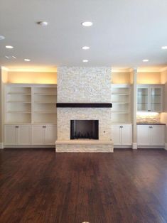 an empty living room with wood flooring and built in bookshelves