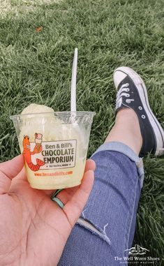 someone is holding an ice cream sundae in their hand while sitting on the grass