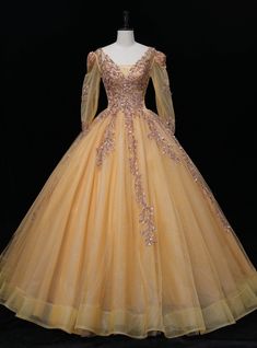 Experience the opulence of modern-day royalty in the dazzling Gold Tulle Long Sleeve Backless Sequins Quinceanera Dress. This enchanting ball gown exudes charm and elegance with its alluring V-neck and full, floor-length skirt that flows gracefully as you move. The delicate tulle fabric, in a radiant gold hue, sets the stage for a truly captivating ensemble. Princess Style Quinceanera Ball Gown For Gala, Ball Gown Quinceanera Dress For Prom Season, Elegant Quinceanera Dress, Glamorous Floor-length Evening Dress For Quinceanera, Princess Tulle Quinceanera Dress For Gala, Tulle Quinceanera Ball Gown For Gala, Tulle Quinceanera Dress Ball Gown For Gala, Tulle Ball Gown For Quinceanera Or Gala, Glamorous Quinceanera Ball Gown For Prom Season