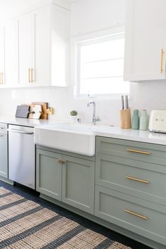 a kitchen with gray cabinets and white counter tops, gold pulls on the faucet