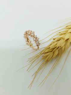 a gold ring sitting on top of a stalk of wheat next to it's ear