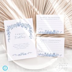 two wedding stationery cards on top of a white plate with bamboo sticks in the background