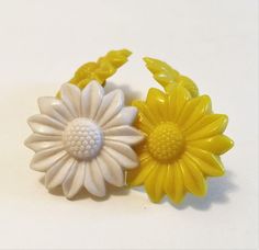 two yellow and white flowers sitting next to each other on top of a white table