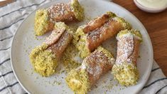 some type of food on a white plate with powdered sugar and cream in the background