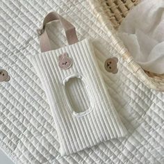 a white bag sitting on top of a bed next to a tissue dispenser