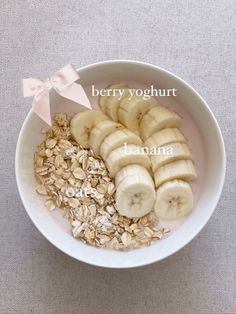 a bowl filled with sliced bananas and oatmeal next to a pink ribbon