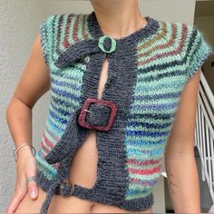 a woman wearing a multicolored knitted sweater with a belt around her waist