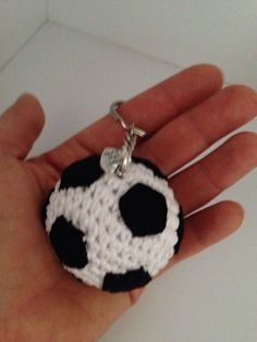 a hand holding a black and white keychain with a soccer ball on it