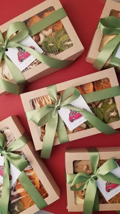 four boxes filled with different types of pastries wrapped in green ribbon and tied around them