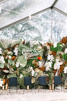 chairs are lined up in front of a wall with flowers and plants on it,