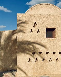 an adobe building with two windows and three triangles on the side, in front of a blue sky