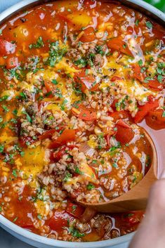 someone is spooning some food out of a pot filled with meat, rice and vegetables